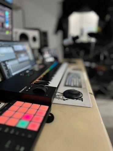 A close-up view of a music production keyboard and controller in a studio.