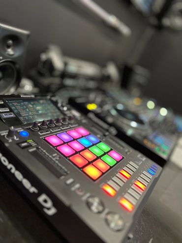 Colorful illuminated DJ controller pads and sliders in a music setup.