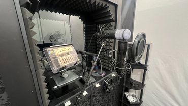 Professional vocal recording booth with microphone, pop filter, and tablet mixer.