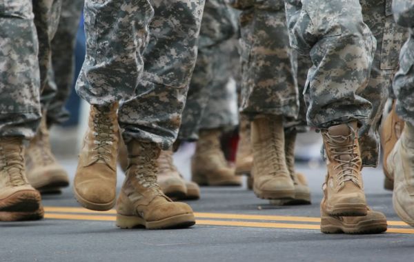 Soldiers in camouflage uniforms marching on pavement.