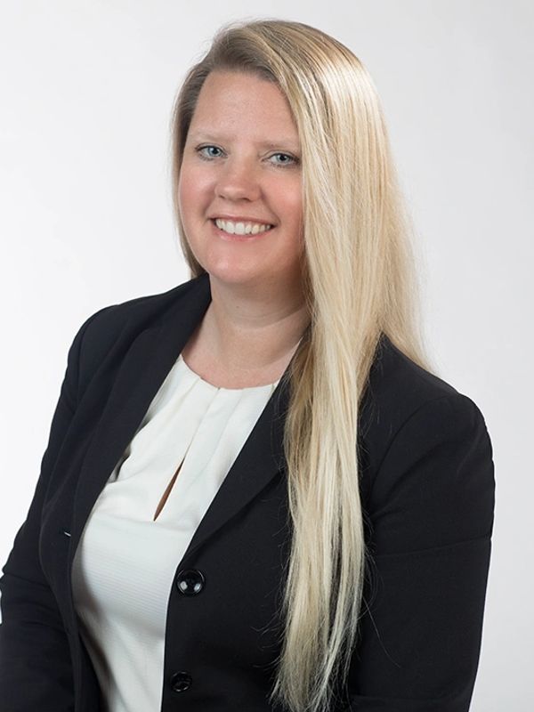 Smiling woman with long blonde hair in business attire.