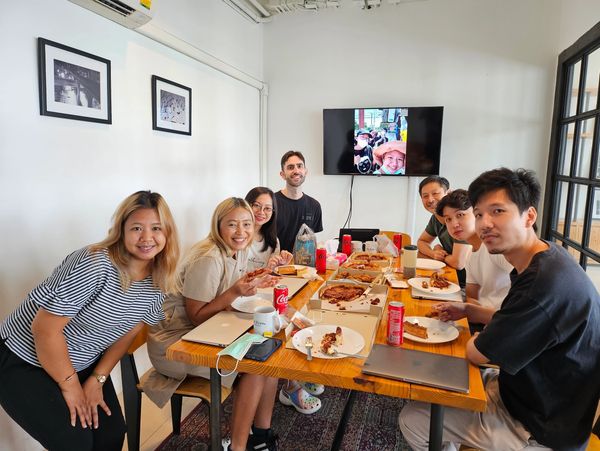 A group of friends enjoying pizza and drinks around a table indoors.