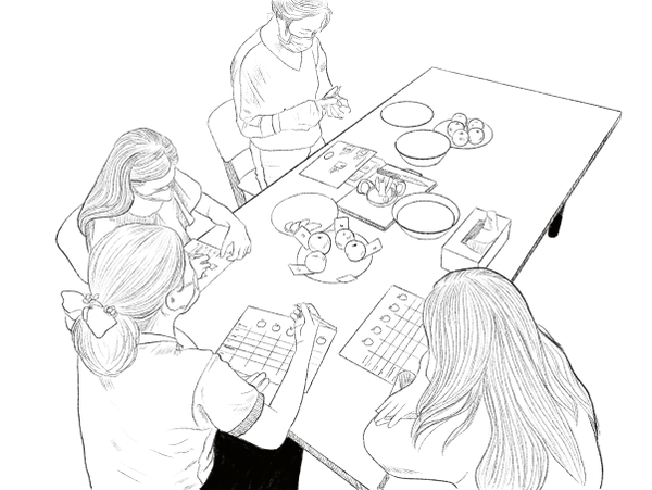 Four girls sitting at a table, playing a board game with game pieces.