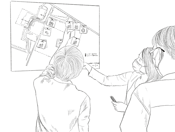 Three people wearing masks study a map on a wall indoors.