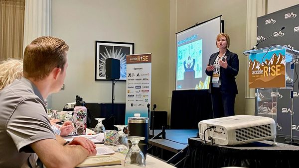 A woman gives a presentation to attentive attendees at a professional conference.