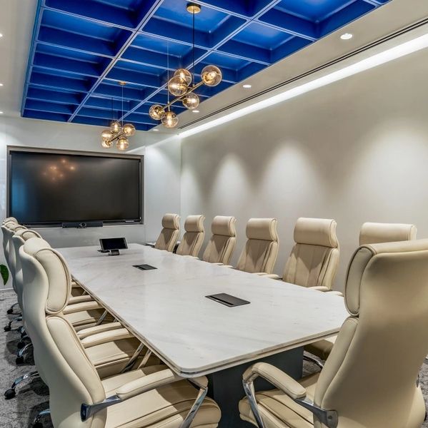 Modern conference room with beige chairs, blue ceiling, and large screen.