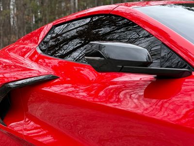 Close-up of a red sports car's side mirror and window.