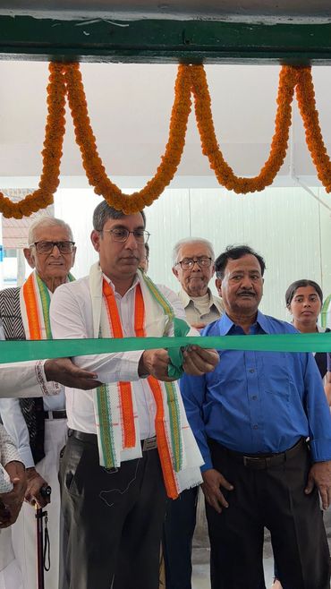 Group cutting a green ribbon at an event inauguration.