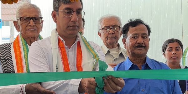 Group cutting a green ribbon at an event inauguration.