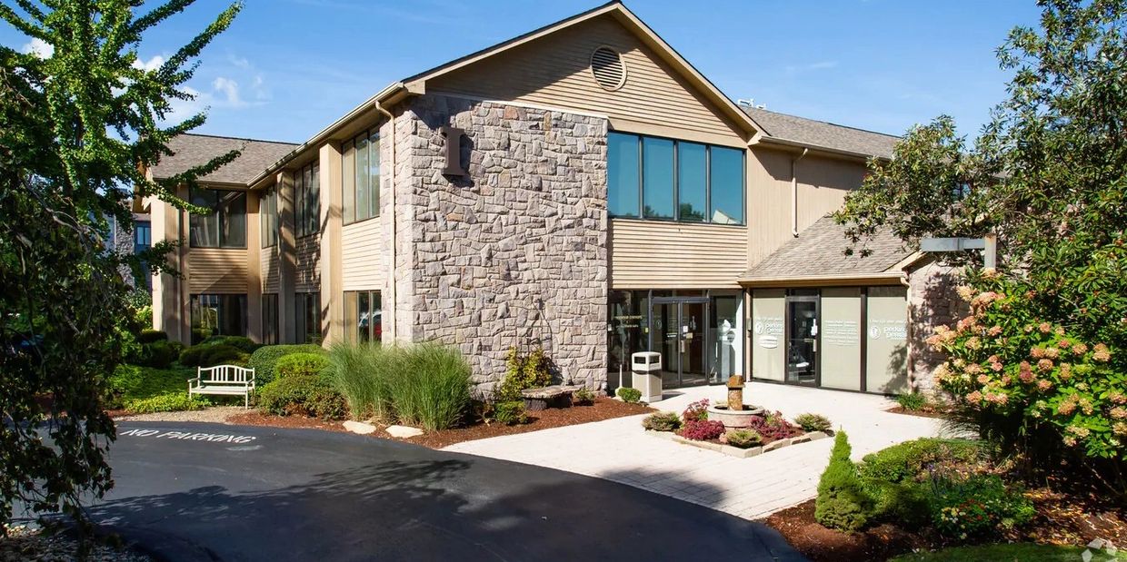 Modern building with stone facade and landscaped entrance.
