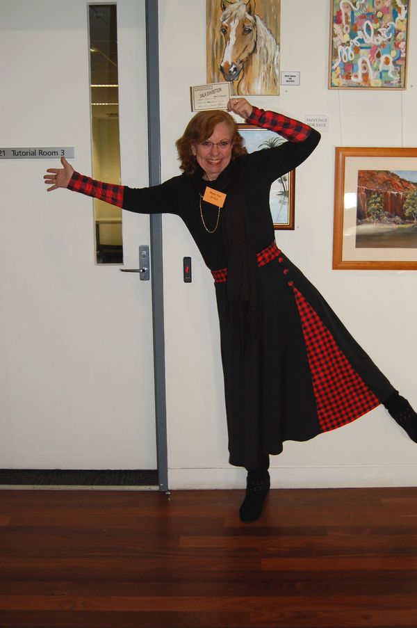 Woman joyfully posing near a door in a black and red dress.