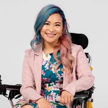 Headshot photo of Akii, wearing a colourful floral outfit with a pink and white blazer.