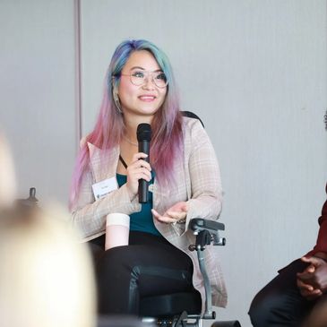Akii holding a microphone, addressing an audience at an International Event.