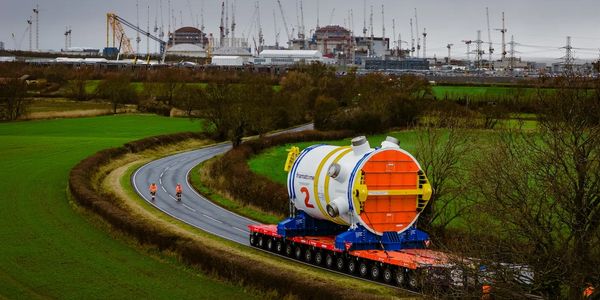 Large industrial equipment transported on a winding rural road.