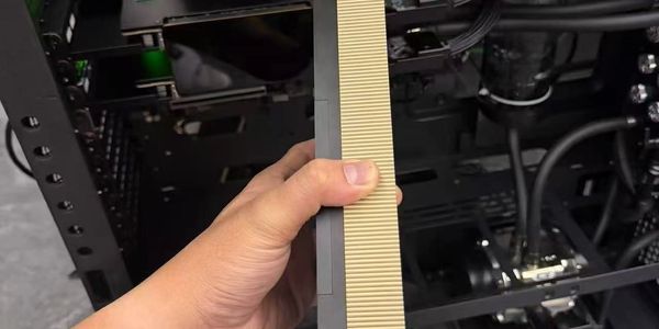 Hand holding a beige and gray computer component.