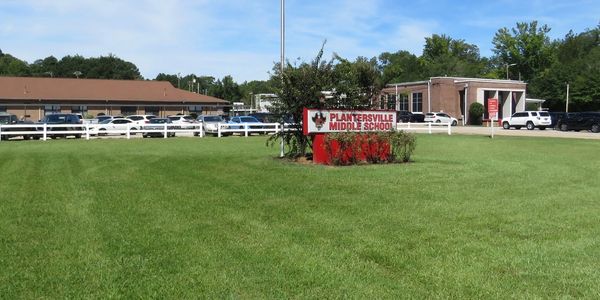 Plantersville Middle School sign on a green lawn under a blue sky.