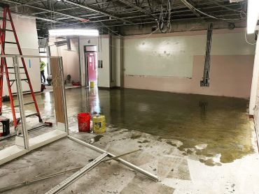 Indoor construction site with wet concrete floor and ladders.