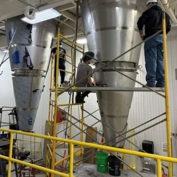 Workers on scaffolding fixing large industrial equipment.