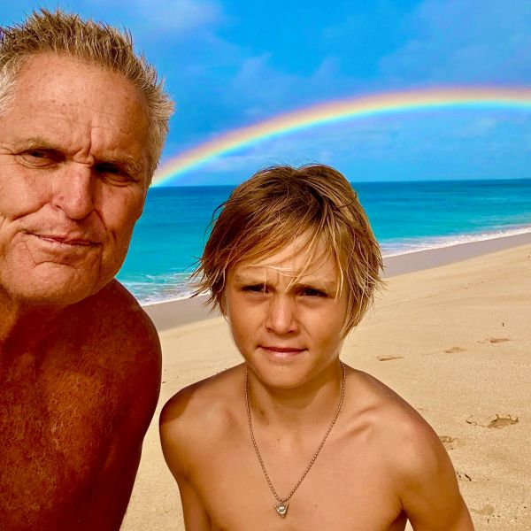Two people on a beach with a rainbow in the background.