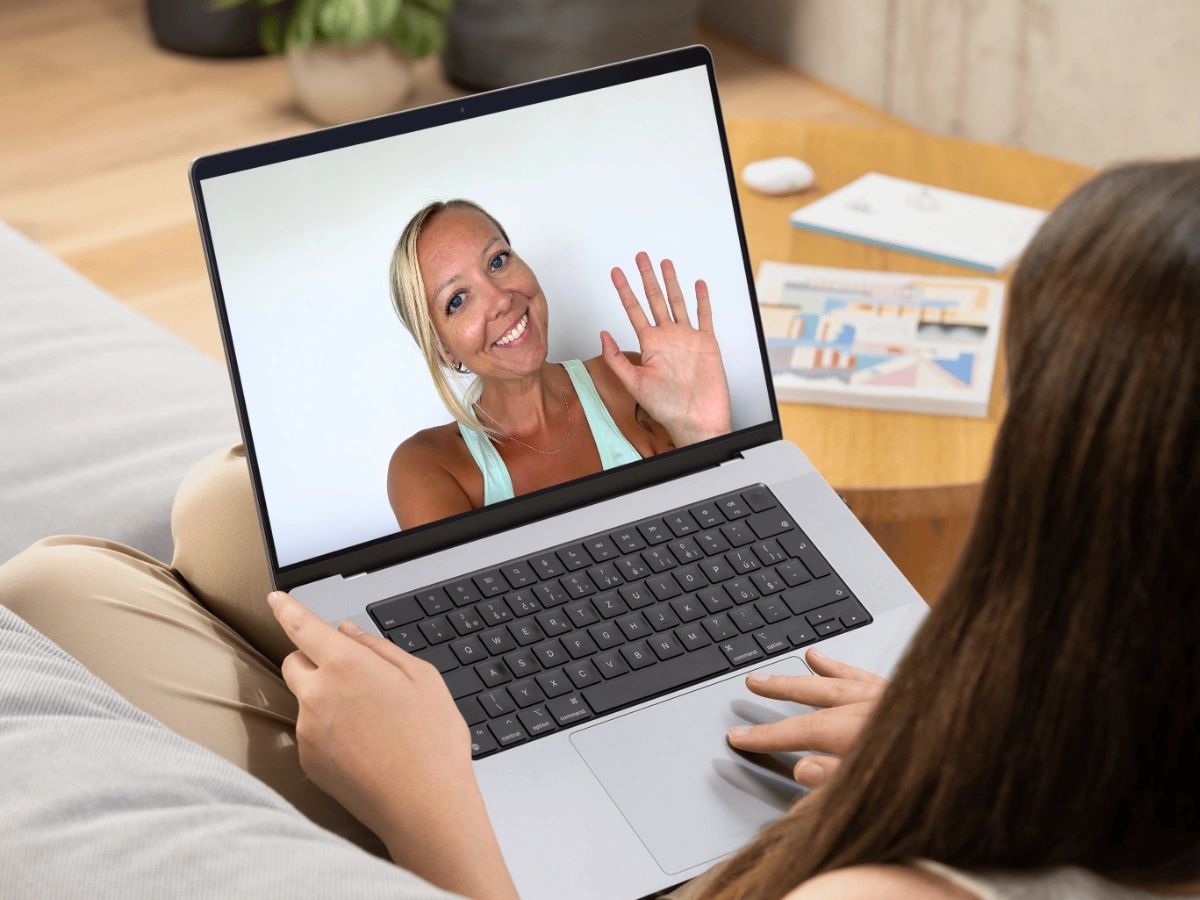 Woman on a laptop video call waving hello.