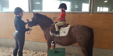 Young rider on pony receiving instruction from riding instructor. 
