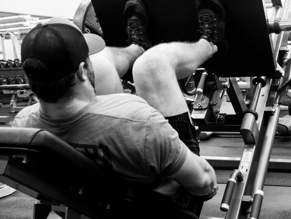 Man working out on a leg press machine in a gym.