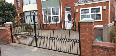 Large metal arched driveway gates with decorative circles and finials