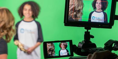A young boy talking with our instructor, in front of a green screen.