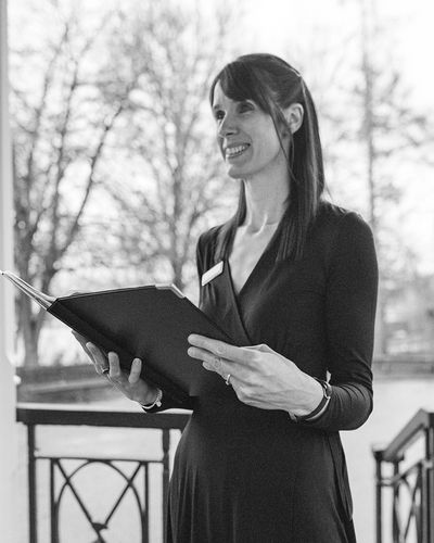 A lady outside holding a folder conducting a wedding ceremony