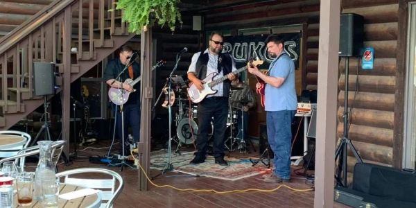 A band performs live on a wooden porch stage.