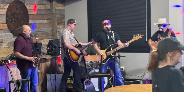 Band performing live with instruments indoors.