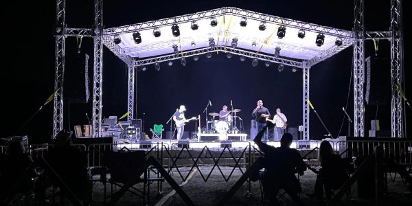 Band performing live on an outdoor stage at night.