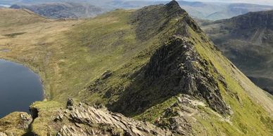 Group of walkers and scrambling on a guided walk on Helvellyn, Striding Edge and Swirral Edge.
