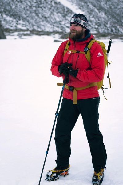 Winter mountaineer with ice axe and crampons hiking through the mountains covered in snow Scotland