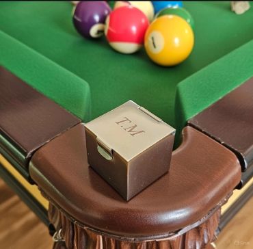 Billiard cue chalk on pool table corner with balls.