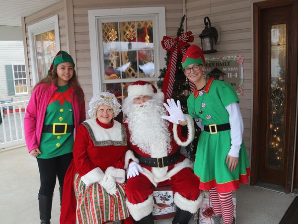 Santa, Mrs. Claus and two elves welcoming guests to the Christkindlmarkt.
