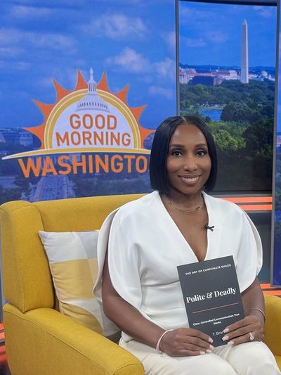 Woman in white holding a book on a TV show set.