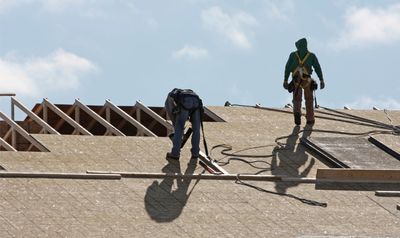 Roofers replacing wood on a roof replacement.