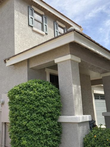 Modern house exterior with textured walls and neatly trimmed greenery.