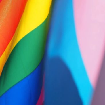 Close-up of a vibrant rainbow pride flag fluttering against a clear sky.