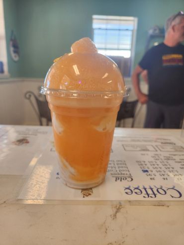 A frothy orange drink in a plastic cup on a counter.