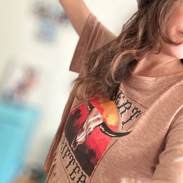 Person wearing a brown shirt with a bull skull graphic and text.