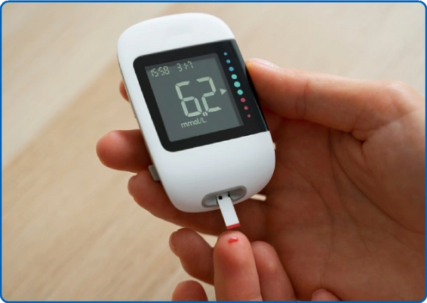 Hand holding a blood glucose meter showing a reading of 6.2 mmol/L.