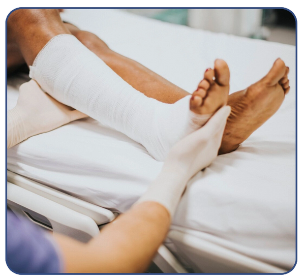Healthcare worker wrapping a patient's leg with a white bandage in a clinical setting.