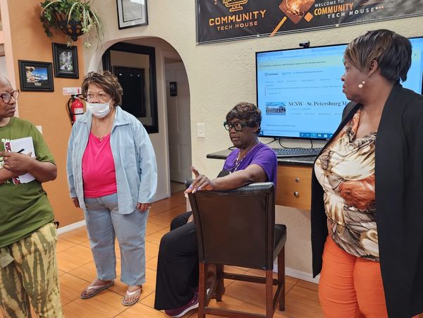 Women engaged in a discussion in a community tech house setting.