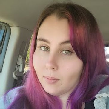 Young woman with purple and pink ombre hair taking a selfie in a car.
