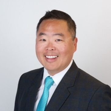 Smiling man in a suit and teal tie.