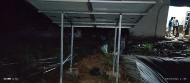 Solar panel installation at night with two people near a lit building.