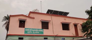 A building with solar panels on the roof and a sign in Oriya script.