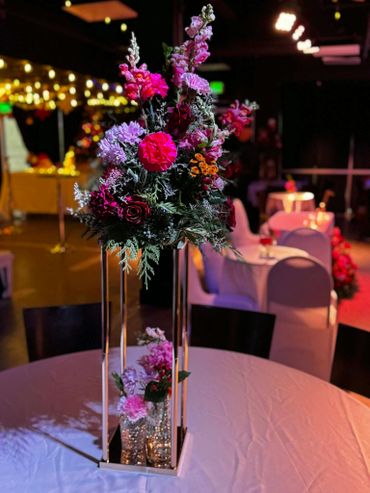 Elegant floral centerpiece on a banquet table with dim ambient lighting.